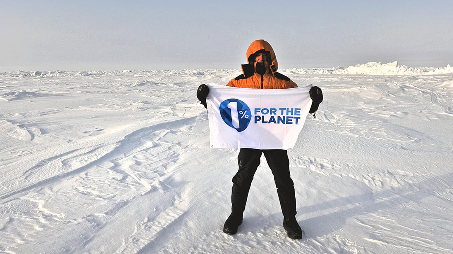 1% for the Planet - Person holding banner in snowy landscape